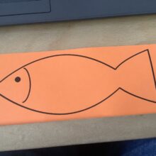 An outline drawing of a fish on orange paper.